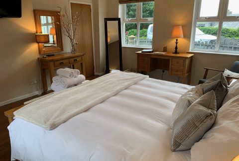 Bedroom with a king-size bed, oak writing desk and windows looking onto the garden