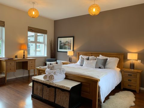 Master bedroom with an oak bed frame, blanket box and bedside lamps